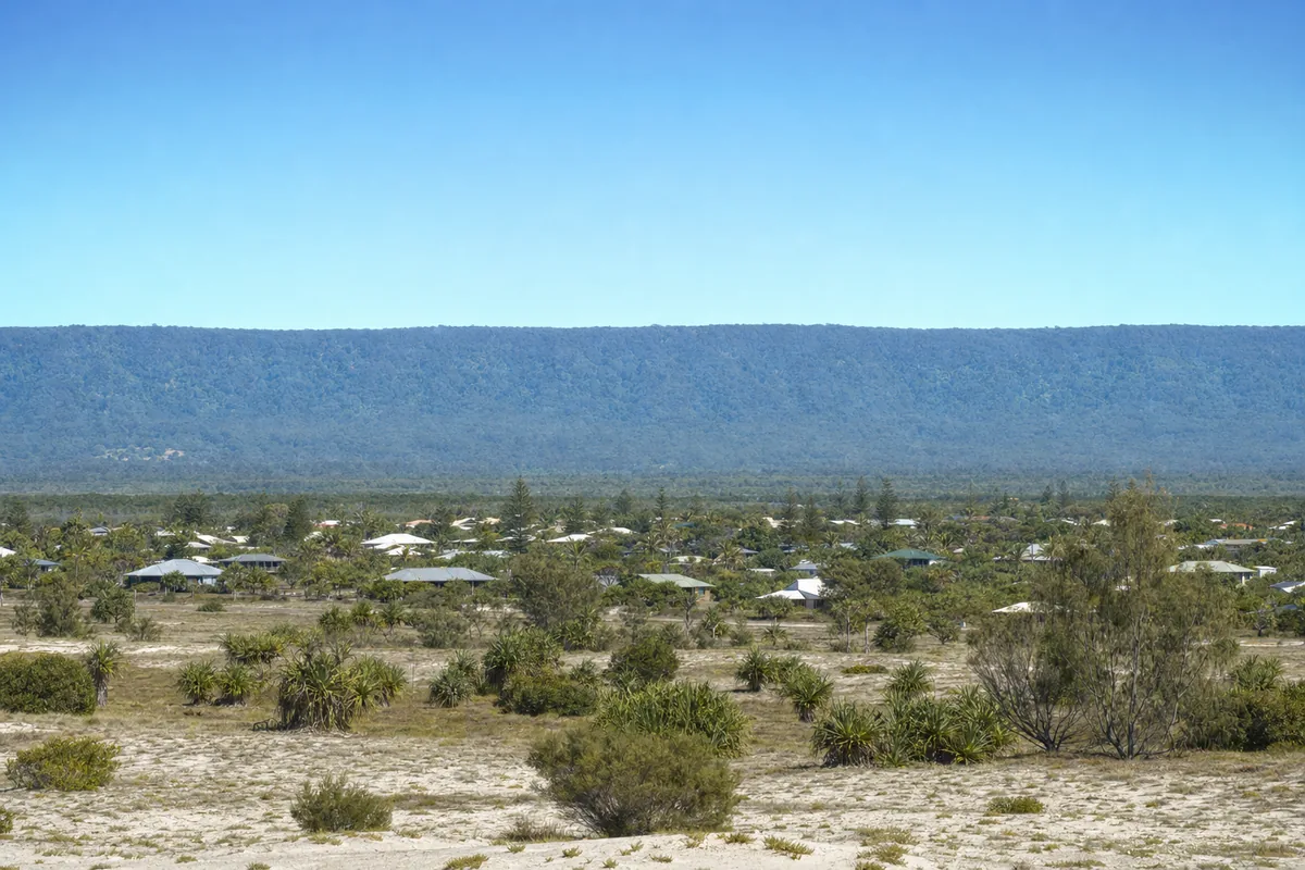 The flat Sunshine Coast coastal plain in the foreground with the forested Blackall Range escarpment running across the horizon behind it, illustrative example